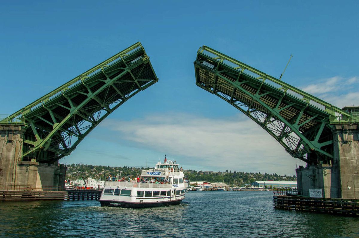 A bascule bridge over Seattle's Ship Canal, raised with a boat passing beneath.