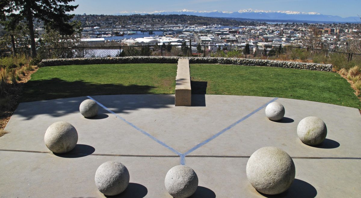 Fremont Peak Park: a concrete overlook plaza with stone spheres, a bench, and a panoramic view toward the Olympic Mountains.